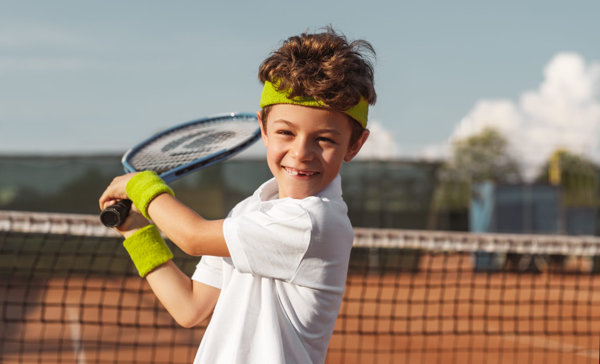 happy boy playing tennis court