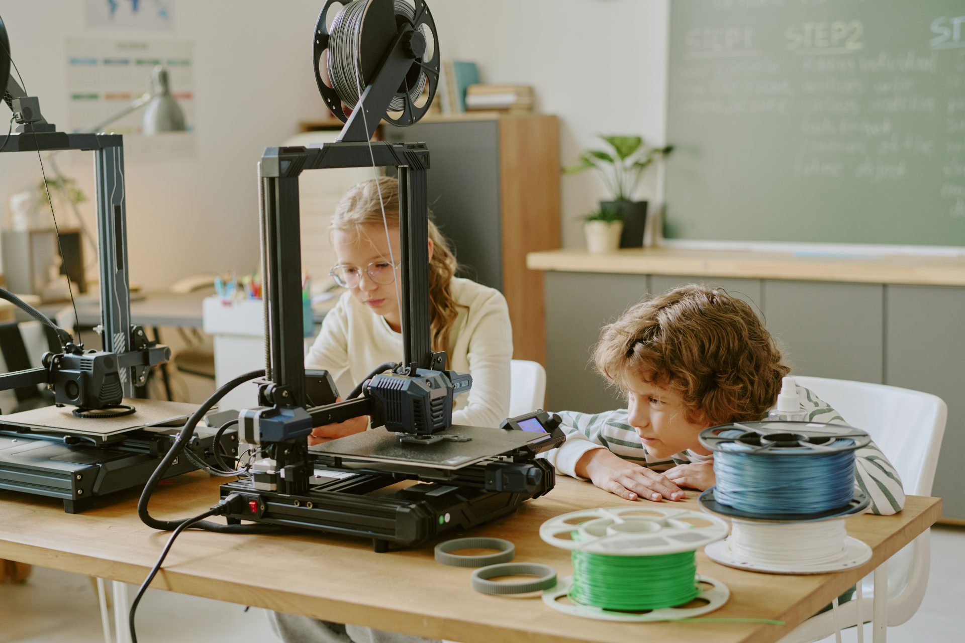 two children working with d printer classroom setting engaged observation